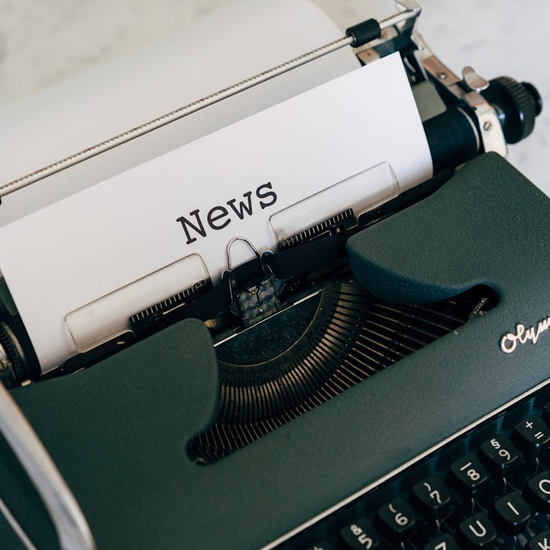Close-up of an antique typewriter with 'News' on paper.